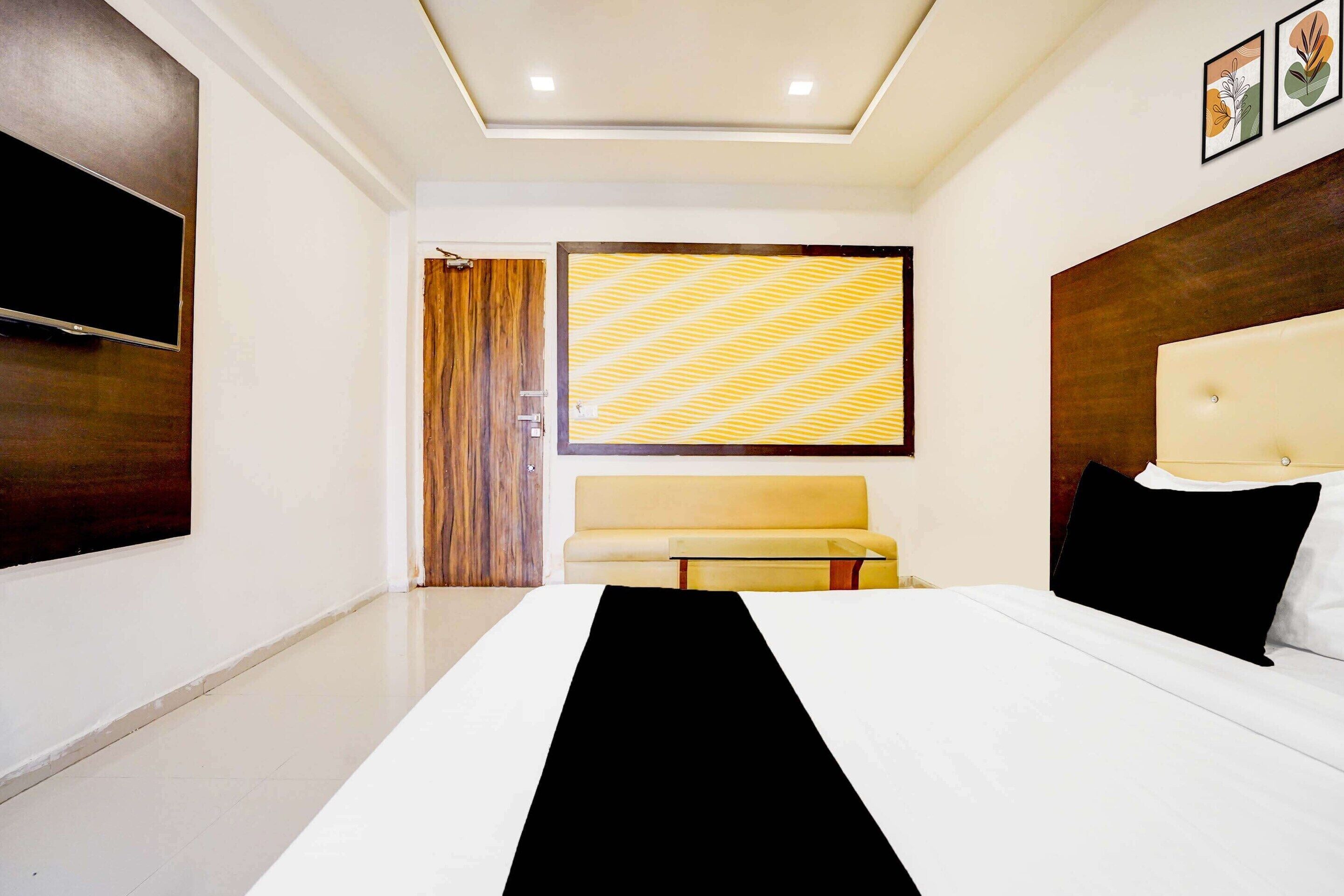 A hotel room with a bed, a TV, a sofa, and a patterned wall.