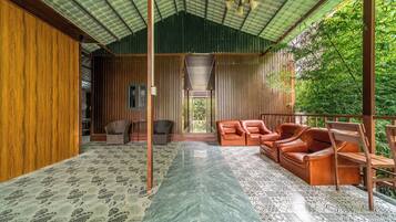 A covered outdoor seating area with wooden furniture and a patterned floor.