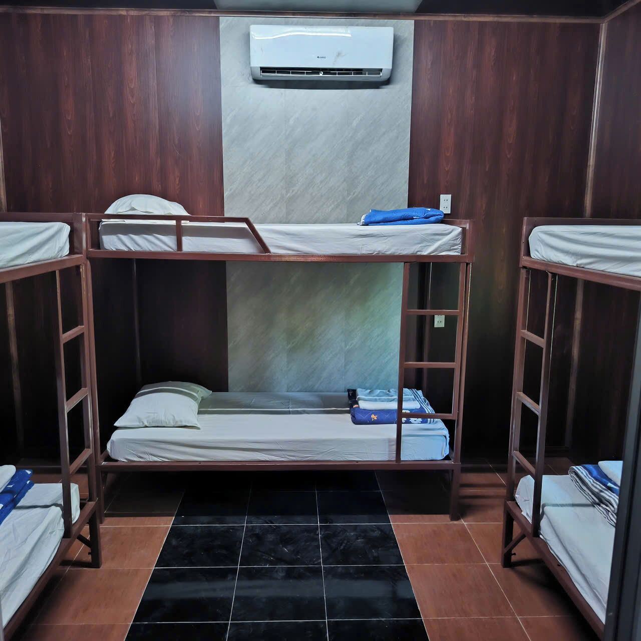 A room with bunk beds, an air conditioning unit, and a tiled floor.