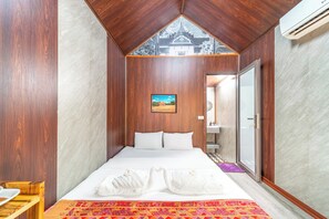 A hotel room with a bed, a painting, a bathroom, and a view of a temple through a window. - Anna Bungalow Vientiane (Vientiane)