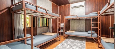 Une chambre avec des lits superposés, des murs en bois, un tapis à motifs et une fenêtre avec des rideaux.