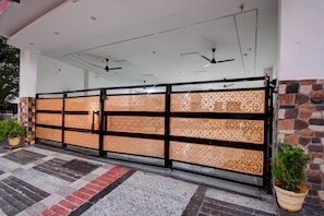 A gated entrance with a patterned screen, ceiling fans, and a stone wall. - Deluxe Gomti Nagar Station Budget In (Lucknow)