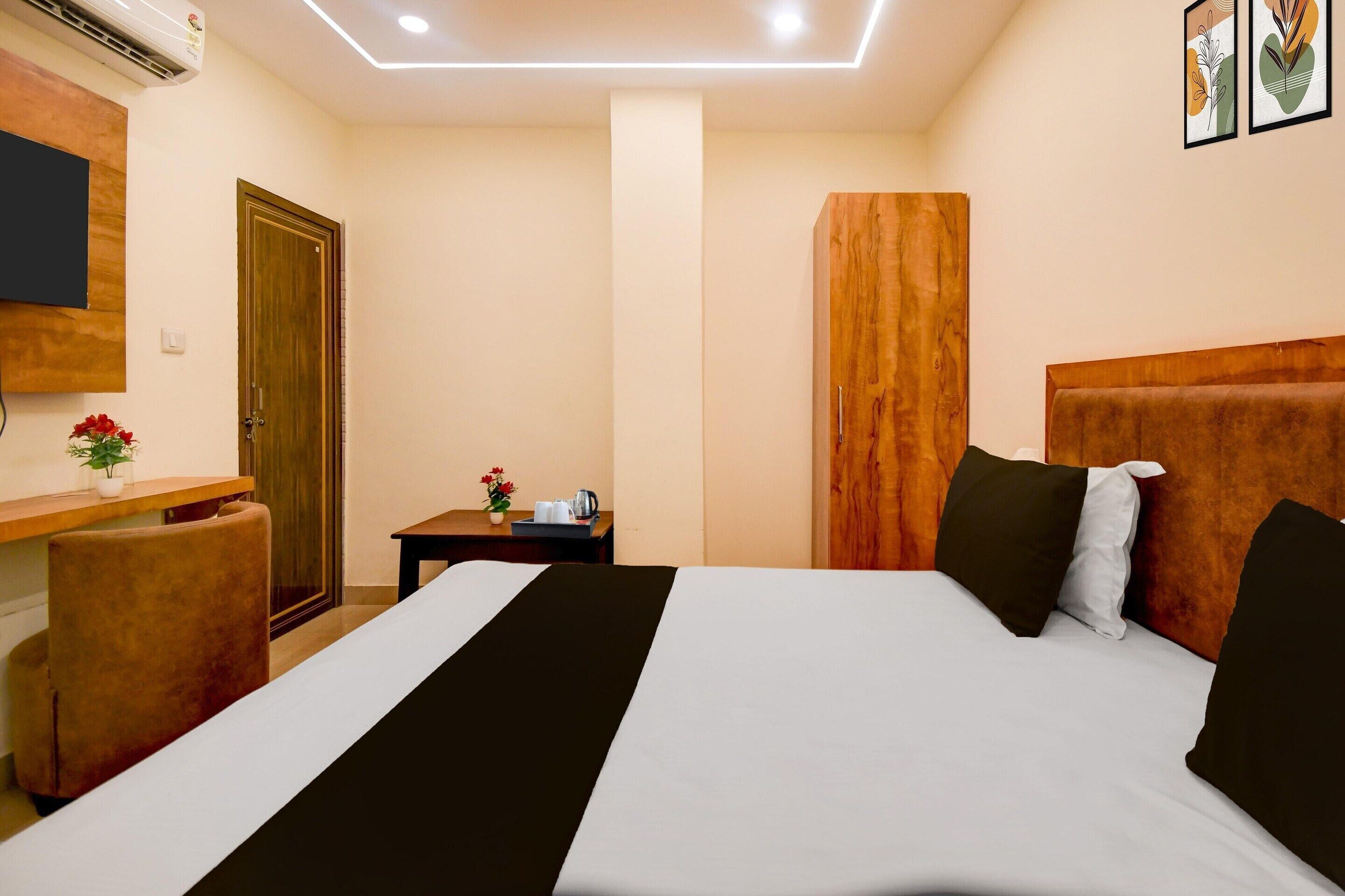 A hotel room with a bed, a desk, a chair, a TV, and a door.