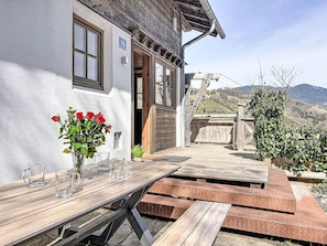 Eine Holzterrasse mit Tisch und Stühlen, ein Holzzaun und Blick auf einen Berg.
