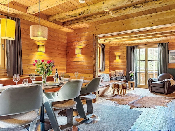 Ein Holzblockhaus-Interieur mit Essbereich, einer Couch und einem Ledersessel.