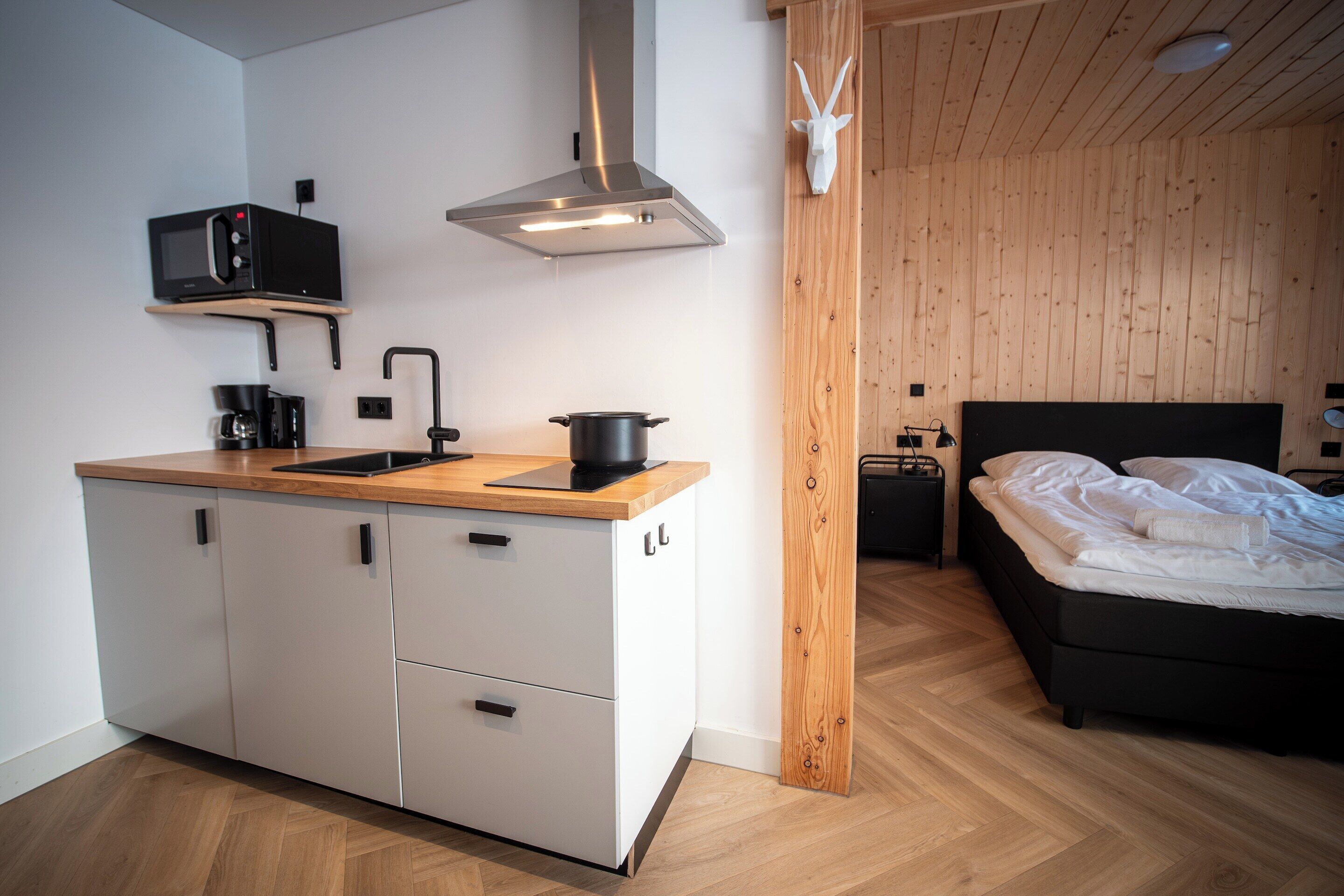 A compact kitchen with a microwave, coffee maker, and a pot on the counter.