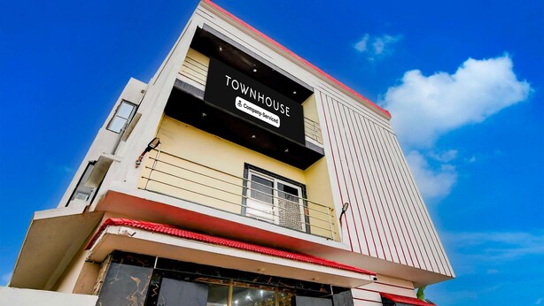 A multi-story building with a sign reading 'TOWNHOUSE' and 'Company Serviced.' - Deluxe With Twin Bed Shri Jagannath Homestay (Puri)