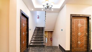 A hallway with marble flooring, a staircase, and two wooden doors with geometric patterns. - Deluxe With Twin Bed Shri Jagannath Homestay (Puri)