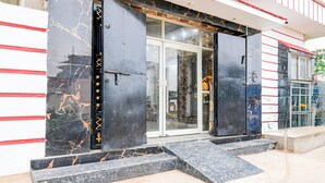 A building entrance with large black doors, a marble floor, and a red and white striped wall. - Deluxe With Twin Bed Shri Jagannath Homestay (Puri)