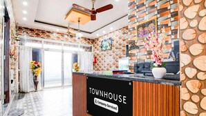 A reception area with a sign reading 'TOWNHOUSE Company-Serviced,' a ceiling fan, and a wall with a patterned design. - Deluxe With Twin Bed Shri Jagannath Homestay (Puri)