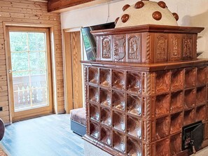 Ein Holzinnenraum mit Kamin, einer Tür mit Glasfeldern und einer Bank.