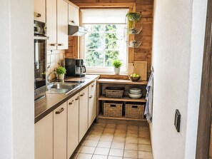 Eine kleine Küche mit Holdekor, einer Kaffeemaschine, einem Spülbecken und einem Fenster mit Pflanzen.
