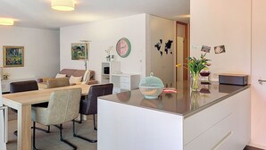 Un soggiorno moderno con zona pranzo, isola della cucina e un grande specchio.