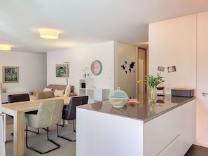 Ein modernes Wohnzimmer mit Essbereich, Kücheninsel und großem Spiegel.