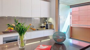 Una cucina moderna con mobili bianchi, un lavello in acciaio inossidabile, un vaso con fiori e una ciotola sul piano di lavoro.