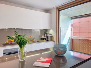 Eine moderne Küche mit weißen Schränken, einer Edelstahl-Spüle, einer Blumenvase und einer Schüssel auf der Arbeitsplatte.