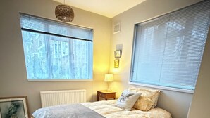 A bedroom with a bed, bedside lamp, and a picture frame on the wall. - Stylish apartment in city centre, excellent link to London by rail, bus & road (Camberley)