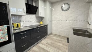 A modern kitchen with a built-in microwave, a yellow kettle, and a stainless steel sink. - Stylish apartment in city centre, excellent link to London by rail, bus & road (Camberley)