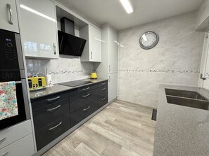 A modern kitchen with a built-in microwave, a yellow kettle, and a stainless steel sink. - Stylish apartment in city centre, excellent link to London by rail, bus & road (Camberley)