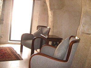 Ein Zimmer mit zwei gepolsterten Sesseln, einem kleinen Holztisch und einem gemusterten Teppich.