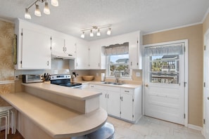 A kitchen with white cabinets, a built-in oven, a sink, and a window with a view.