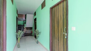 A hallway with a green wall, a wooden door, and two potted plants. - Super Hotel O Dadri Main Greater Noida (Greater Noida)