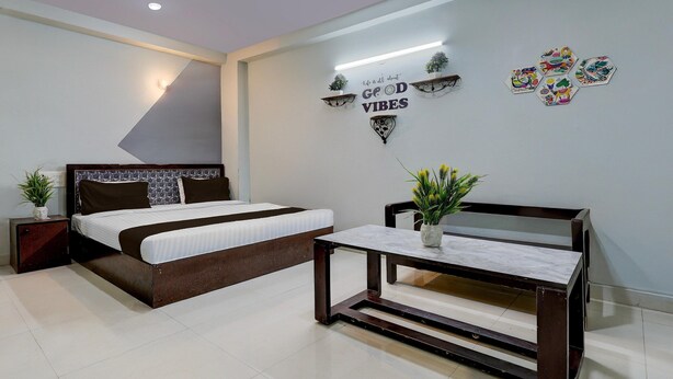 A bedroom with a bed, bedside table, and a wall-mounted shelf with decorative items. - Super Hotel O Dadri Main Greater Noida (Greater Noida)