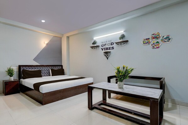 A bedroom with a bed, bedside table, and a wall-mounted shelf with decorative items.