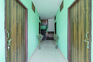 A hallway with two wooden doors, a tiled floor, and a staircase leading to an upper level.
