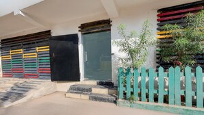 A building entrance with a set of steps leading to a door, a small garden area with a fence, and a bamboo plant. - Super Hotel O Dadri Main Greater Noida (Greater Noida)