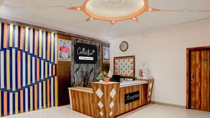 A reception desk with a sign reading 'Collection Company-Serviced,' a clock on the wall, and a door labeled '107.' - Deluxe Pushp Vatika (Varanasi)