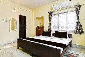 A bedroom with a bed, an air conditioner, a window with curtains, a mirror, and a wardrobe. - Super Hotel O Mukundapur (Kolkata)