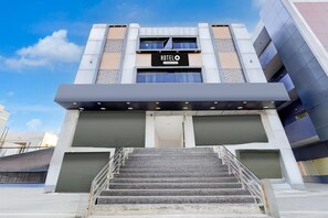 Ein Hotel Eingang mit einer Treppe, einem Schild mit der Aufschrift 'HOTEL O & Company Serviced' und einem modernen architektonischen Design.
