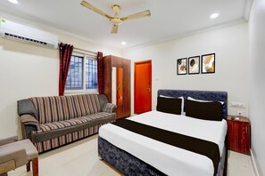 Ein Schlafzimmer mit einem Bett, einer Couch, einem Deckenventilator, einer Klimaanlage und gerahmten Bildern an der Wand.