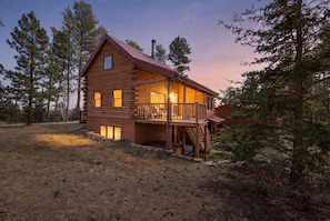 A log cabin with a balcony, a chimney, and a porch.
