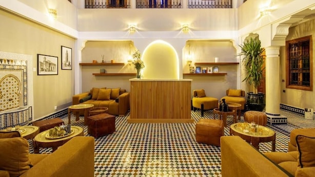 Una hall con pavimento a scacchi, divani, una reception e un balcone.
