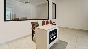 A conference room with a large window, a ceiling fan, and a sign indicating it's a company service area. - Collection O RS Puram North Railway (Coimbatore)