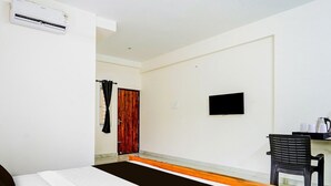 A hotel room with a bed, a desk with a chair, a TV, and an air conditioning unit. - Collection O RS Puram North Railway (Coimbatore)