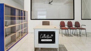 A conference room with a large screen, a ceiling fan, and a sign indicating it's company-serviced. - Collection O RS Puram North Railway (Coimbatore)