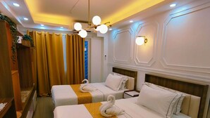 Ett hotellrum med två sängar, en sänggavel i trä, ett litet skrivbord och ett fönster med gardiner.