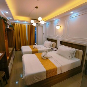 Ein Hotelzimmer mit zwei Betten, einem Holzkopfstück, einem kleinen Schreibtisch und einem Fenster mit Vorhängen.