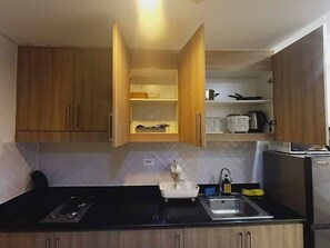 Eine kleine Küche mit Holzschränken, einer schwarzen Arbeitsplatte, einem Spülbecken und einem Herd.