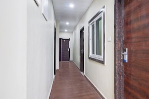 A hallway with a wooden floor, white walls, and a door at the end. - Super Deluxe Room Hotel Rans (Hyderabad)