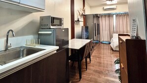 Cocina compacta con fregadero, microondas y refrigerador. Hay un comedor con mesa y sillas.