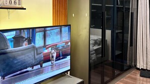 Ett modernt rum med en platt-TV, en väggpanel av träribbor, en garderob med glasdörrar och en säng.