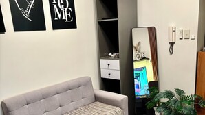 Ett modernt vardagsrum med en grå soffa, en mjuk matta, ett grått skåp, en spegel och två krukväxter.