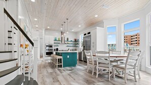 Una cocina moderna con una isla central, armarios blancos y vistas a edificios.