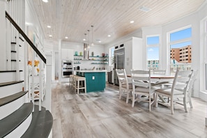 Una cocina moderna con una isla central, armarios blancos y vistas a edificios.