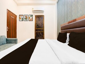 Ein Hotelzimmer mit Bett, einer Sitzecke, einer Tür und einer Wandklimaanlage.