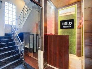 A hotel reception area with a staircase, a reception desk, and a wall-mounted sign. - Saver Double OYO Hotel O Sankat Mochan (Varanasi)